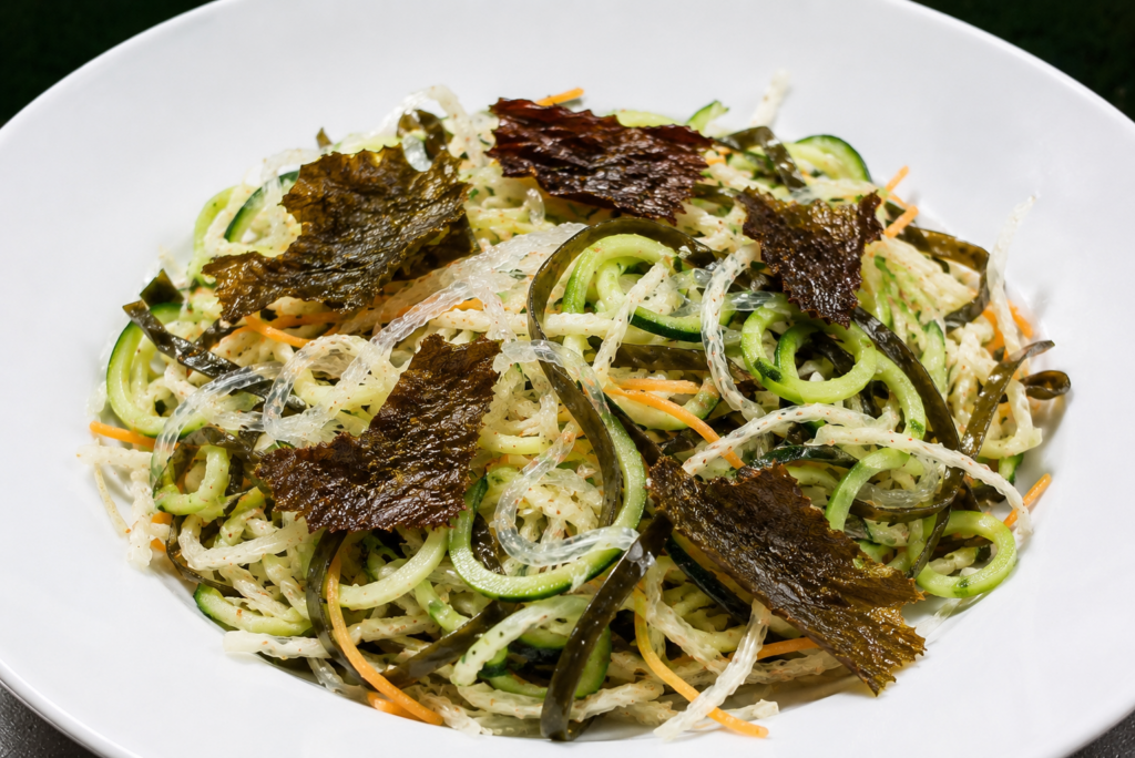 „Grüner Algensalat mit Dulse-Crunch“ greift die Idee klassischer asiatischer Algensalate auf und interpretiert sie mit Gemüse und Zutaten aus der europäischen Küche neu. Meeresspaghetti, Spitzkohl, Zucchini und knusprige Dulse sorgen für Frische, Abwechslung und einen besonderen Genuss zwischen Garten und Meer.
